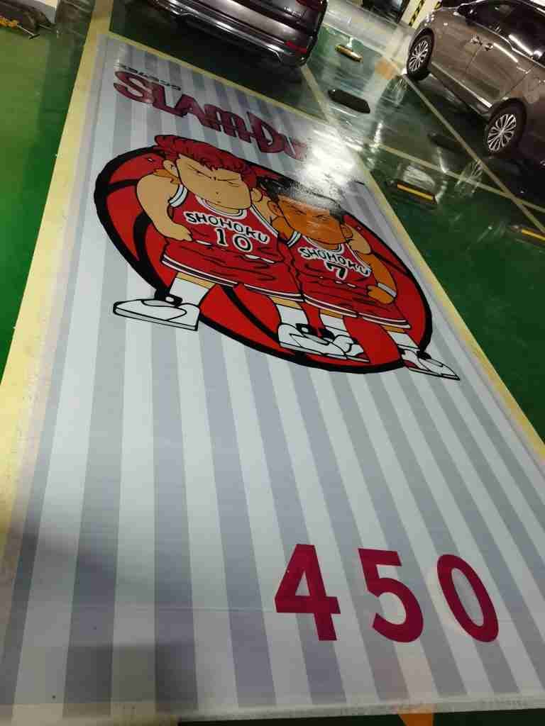 A large full-color graphic printed directly onto a parking structure floor, with a bay number printed alongside it